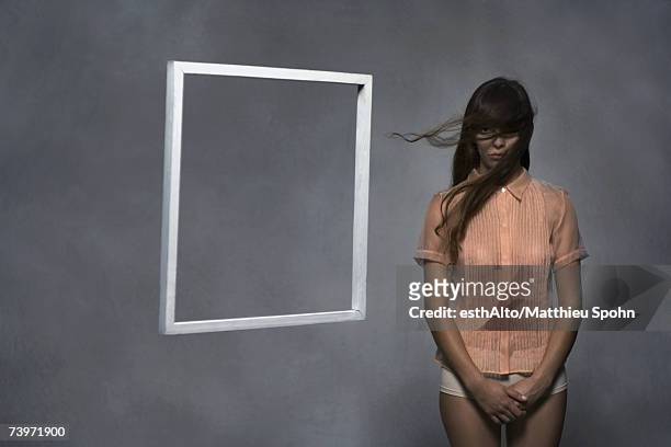 woman standing in shirt and underwater, frame floating next to her - blank frame stockfoto's en -beelden