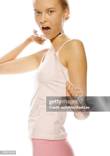 young woman standing with measuring tape around neck and mouth open - women being strangled foto e immagini stock