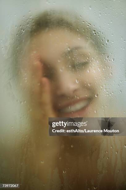 woman behind shower door, wiping face - mirror steam stockfoto's en -beelden