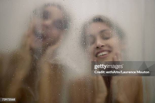 two women behind shower door, wiping faces - mirror steam stockfoto's en -beelden