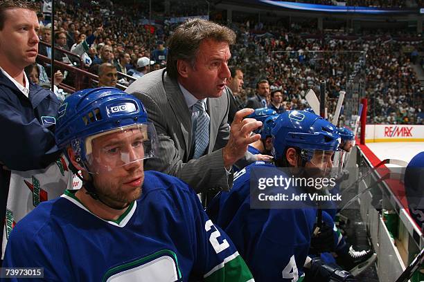 Assistant coach Rick Bowness of the Vancouver Canucks talks to Mattias Ohlund and Brent Sopel on the bench against the Dallas Stars during Game 7 of...