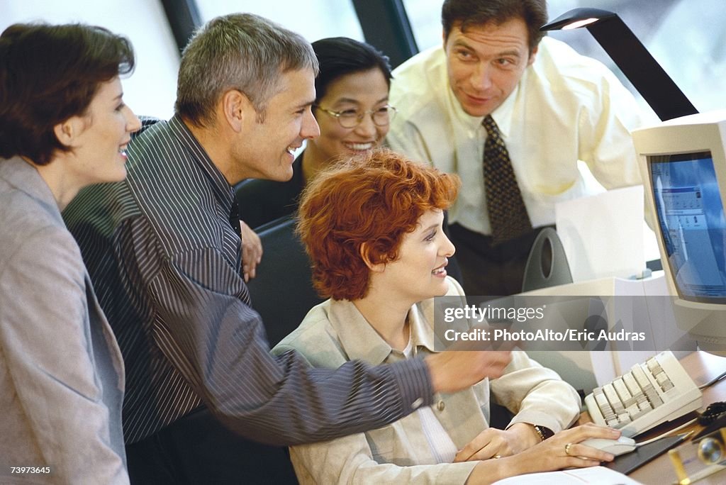 Business associates grouped around computer