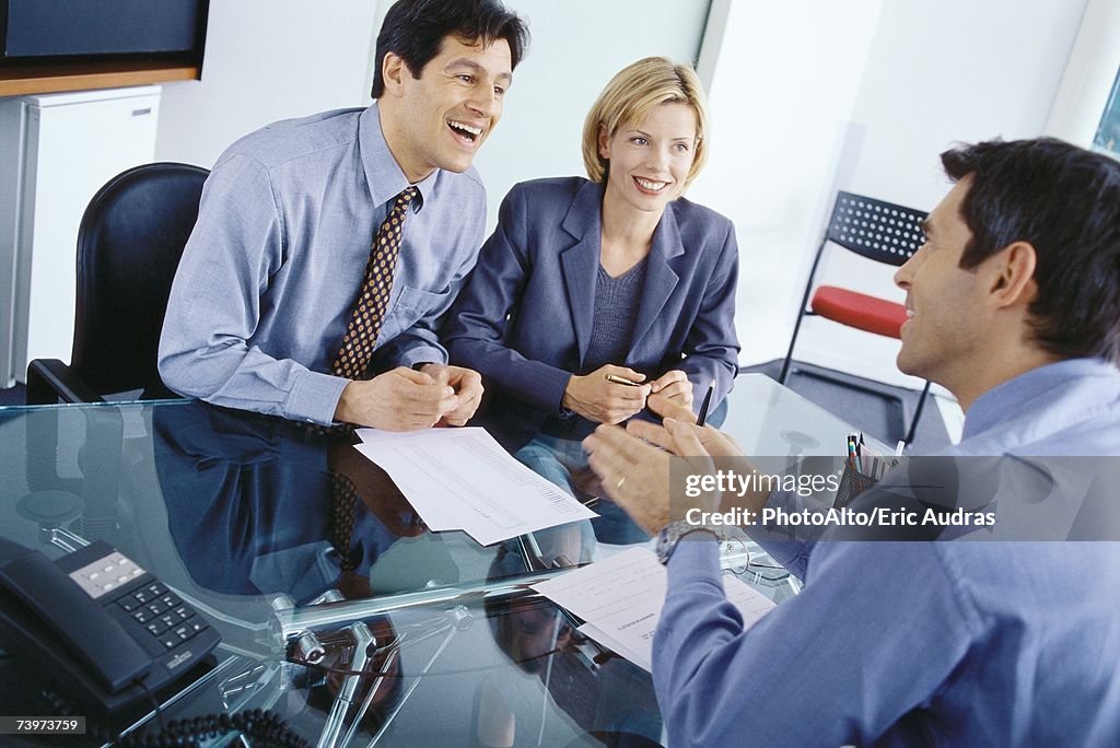 Professional couple having meeting with businessman, discussing documents