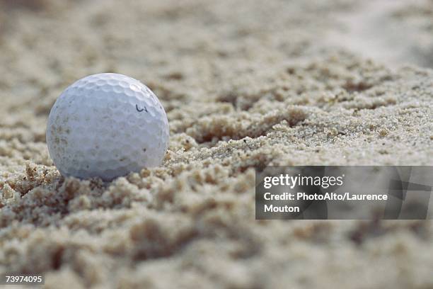 golf ball in sand, close-up - golf bunker stock-fotos und bilder