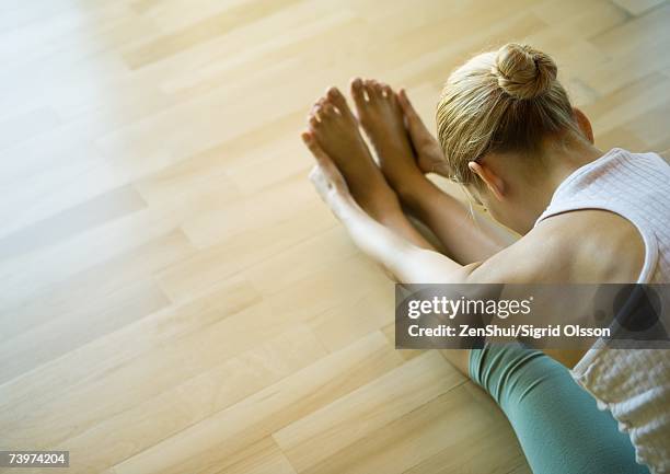 yoga class, woman doing seated forward bend - zehenspitzen berühren stock-fotos und bilder