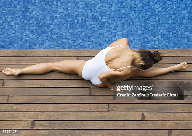 young woman doing splits by edge of pool, high angle view - spagat stock-fotos und bilder