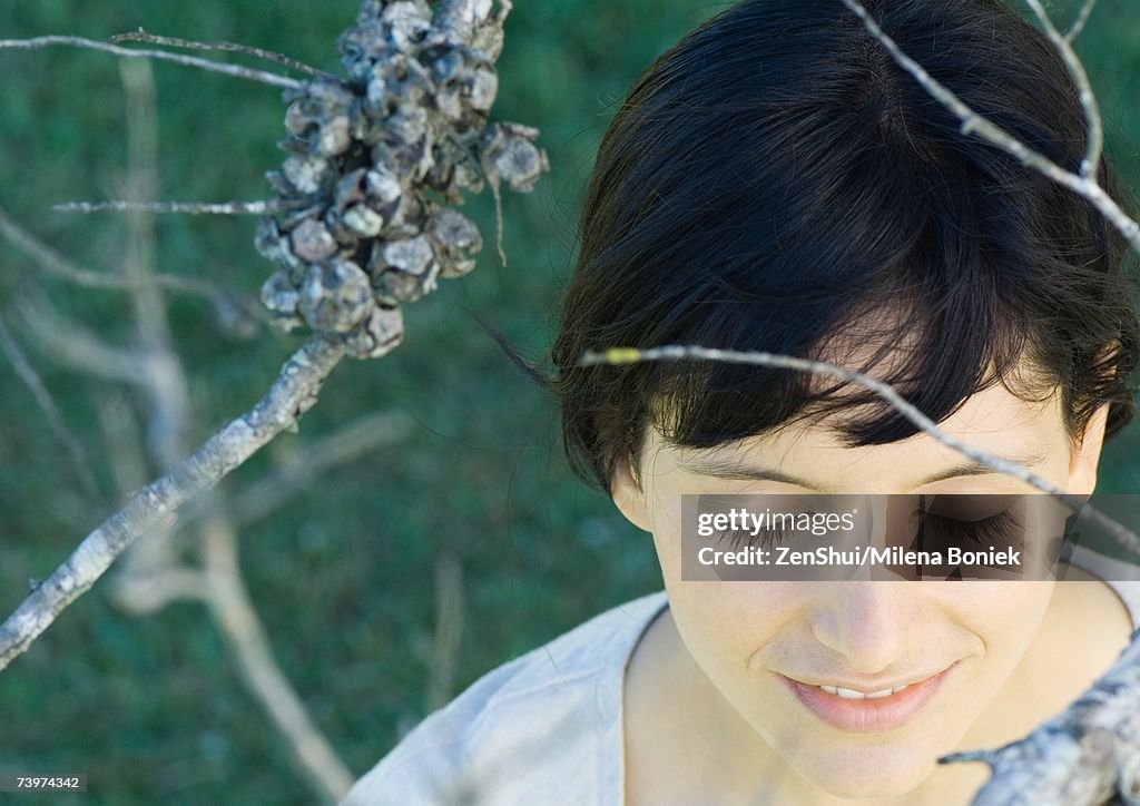 Woman standing amongst dry branches, head and shoulders