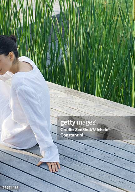 woman sitting on deck, partial view - timber deck stock-fotos und bilder