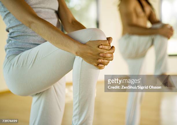 yoga class standing holding knees - human knee stock pictures, royalty-free photos & images