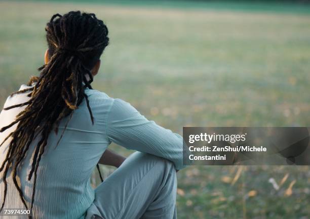 man with dreadlocks sitting outside, rear view - cabello rastafari fotografías e imágenes de stock