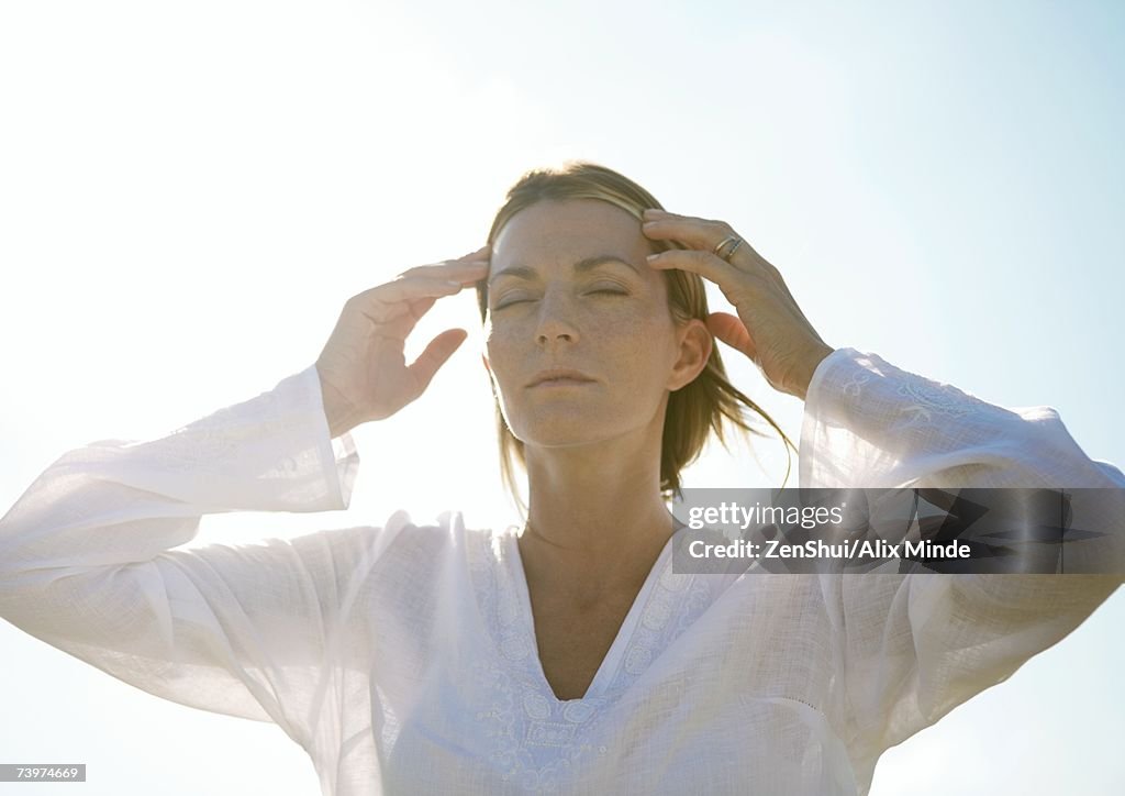 Woman with hands touching temples