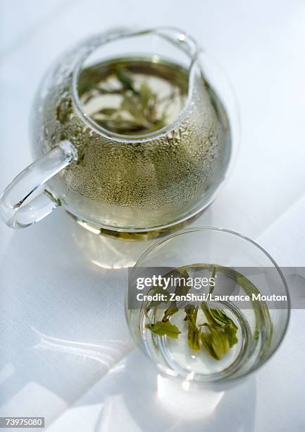 green tea steeping in tea pot and cup - grüner tee stock-fotos und bilder