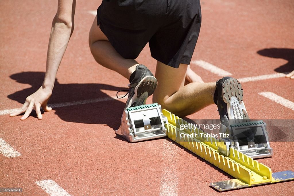 Male athlete in starting blocks on a running track