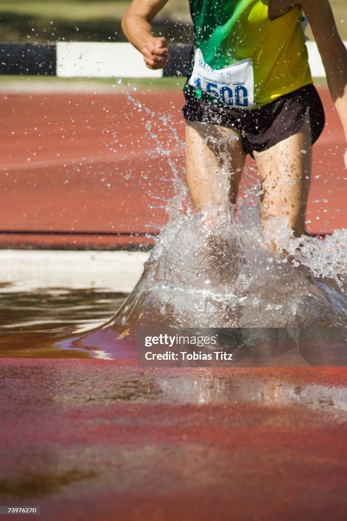 Man in water jump during steeplechase event