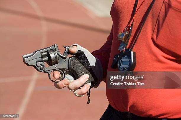 man holding a starting gun on a running track - startschot stockfoto's en -beelden