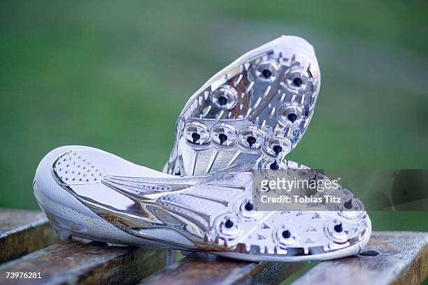 pair of running spikes on a bench - metallic shoe stock pictures, royalty-free photos & images