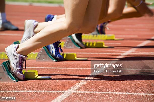 female athletes with feet in starting blocks on a running track - startblok atletiek stockfoto's en -beelden