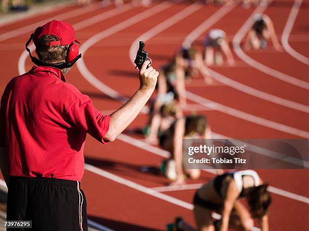 race official holding a starting gun at the beginning of a track event - startschot stockfoto's en -beelden