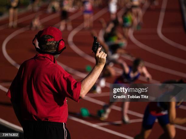 race official holding a starting gun at the beginning of a track event - startschot stockfoto's en -beelden