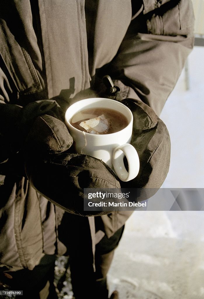 Man wearing ski wear and holding a cup of tea