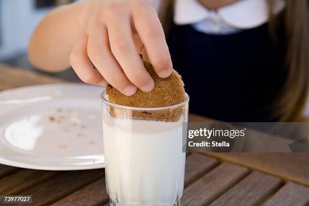 child dipping a biscuit into a glass of milk - kid middle finger stock-fotos und bilder