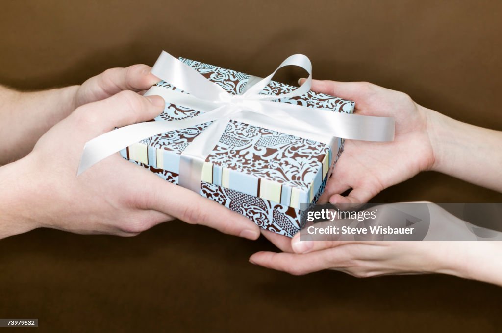 Man giving gift to woman, close-up of hands