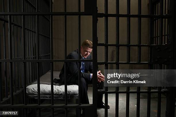 mature businessman sitting on bed in prison cell - gevangene stockfoto's en -beelden