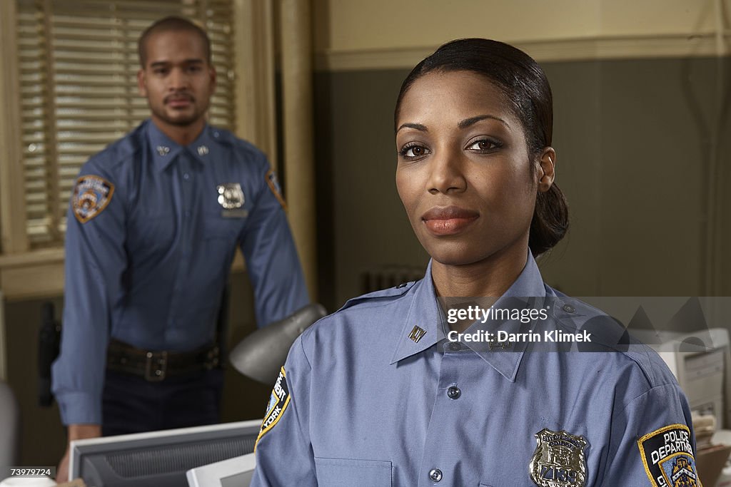 Young policewoman and young policeman in office, portrait