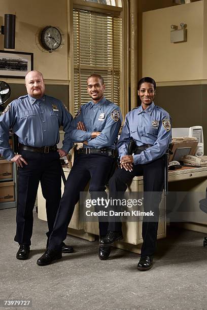 three police officers in police station, smiling, portrait - police sitting stock-fotos und bilder