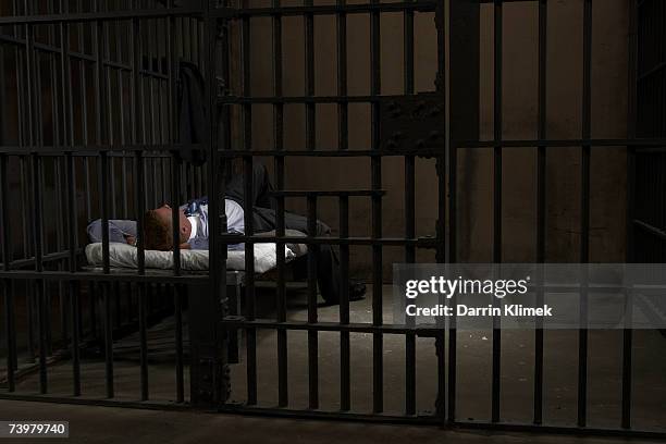 mature man lying on bed in prison cell, rear view - gevangene stockfoto's en -beelden