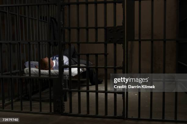 mature man lying on bed in prison cell, rear view - jail bed stock pictures, royalty-free photos & images