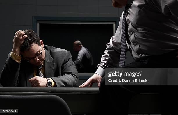 two men sitting at desk in interrogation room - interrogatorio foto e immagini stock