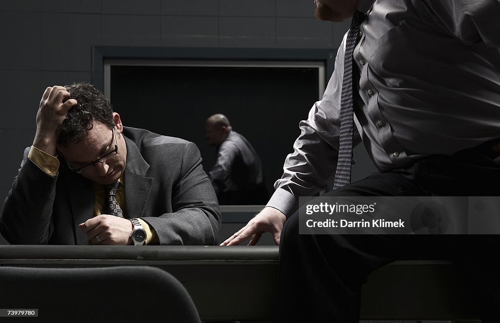 Two men sitting at desk in interrogation room