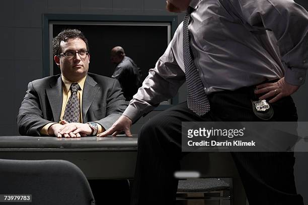 two men sitting at desk in interrogation room - interrogation stock pictures, royalty-free photos & images