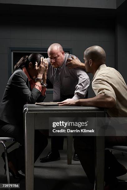 two men and handcuffed woman at desk in interrogation room - interrogation stock pictures, royalty-free photos & images