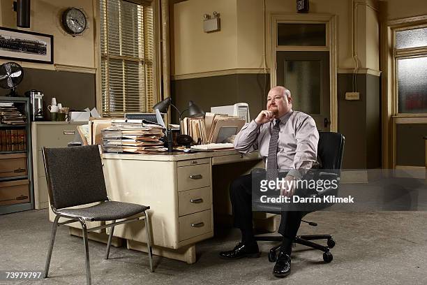 man sitting at desk in office - investigatore foto e immagini stock