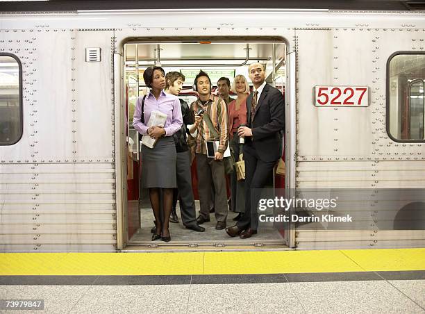 medium group of people standing in subway train doorway - metrostation stockfoto's en -beelden