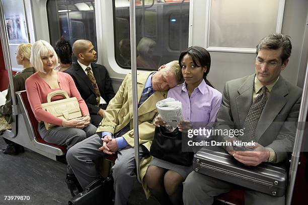 people in subway train, man resting head on woman's shoulder - woman 45 sleeping stock-fotos und bilder