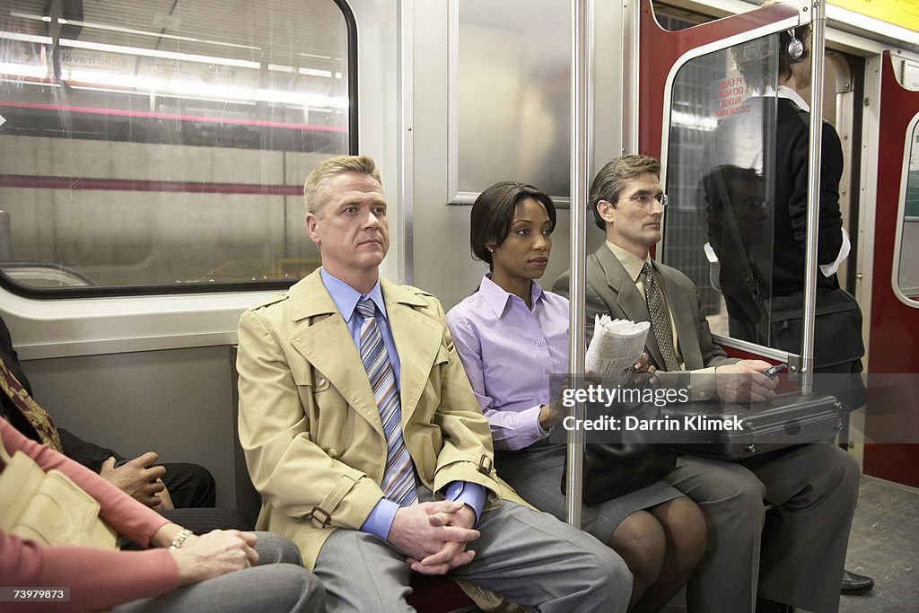 People in subway train, sitting side by side