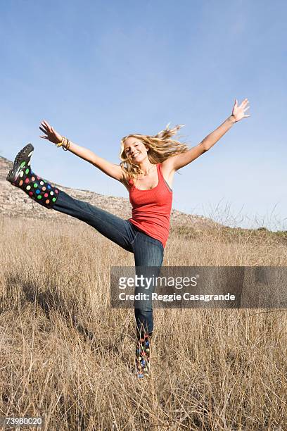 young woman high-kicking in grassland, smiling, portrait - high kick stock pictures, royalty-free photos & images