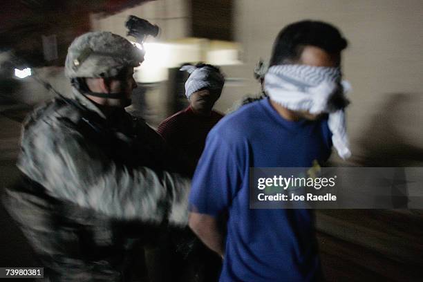 Army soldier of the D-CO 2/325 AIR 82nd Airborne Division walks with detainees during an early morning raid on homes April 26, 2007 in Baghdad, Iraq....