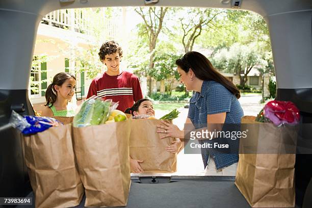 family unloading groceries from car - soccer mom stock pictures, royalty-free photos & images