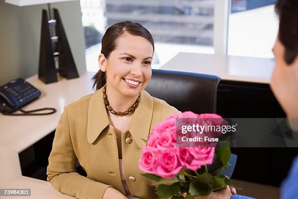 businessman giving businesswoman roses - administrative professionals day stockfoto's en -beelden