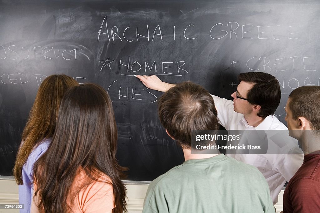 Lecturer writing on blackboard for a group of students