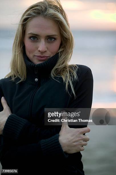 woman standing with arms crossed on a beach - blonde blue eyes stock-fotos und bilder