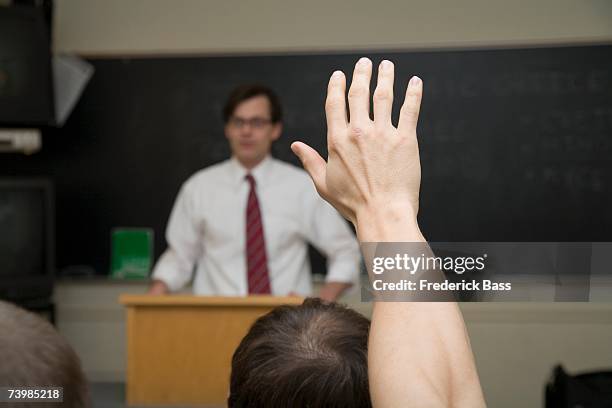 student with hand raised in lecture room - back of heads stock pictures, royalty-free photos & images