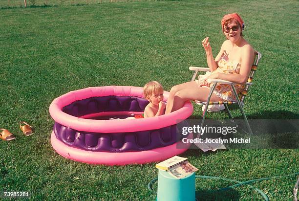 mother and son together in a wading pool - women swimming pool retro stock pictures, royalty-free photos & images