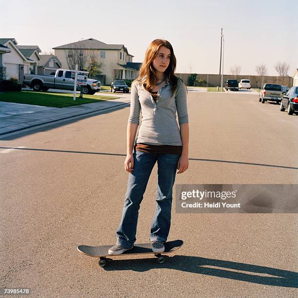 teenage girl standing on skateboard in the street - mädchen 14 jahre stock-fotos und bilder