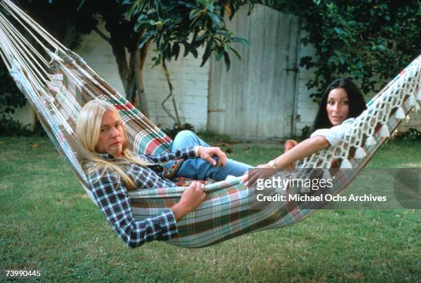 Rock guitarist Gregg Allman and enetertainer Cher pose for a portrait in a hammock at their home on October 30, 1977 in Beverly Hills, California.
