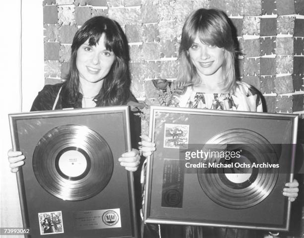 Ann Wilson and Nancy Wilson of the rock and roll band "Heart" pose for a portrait holding gold records they were awarded by the RIAA for a milestone...